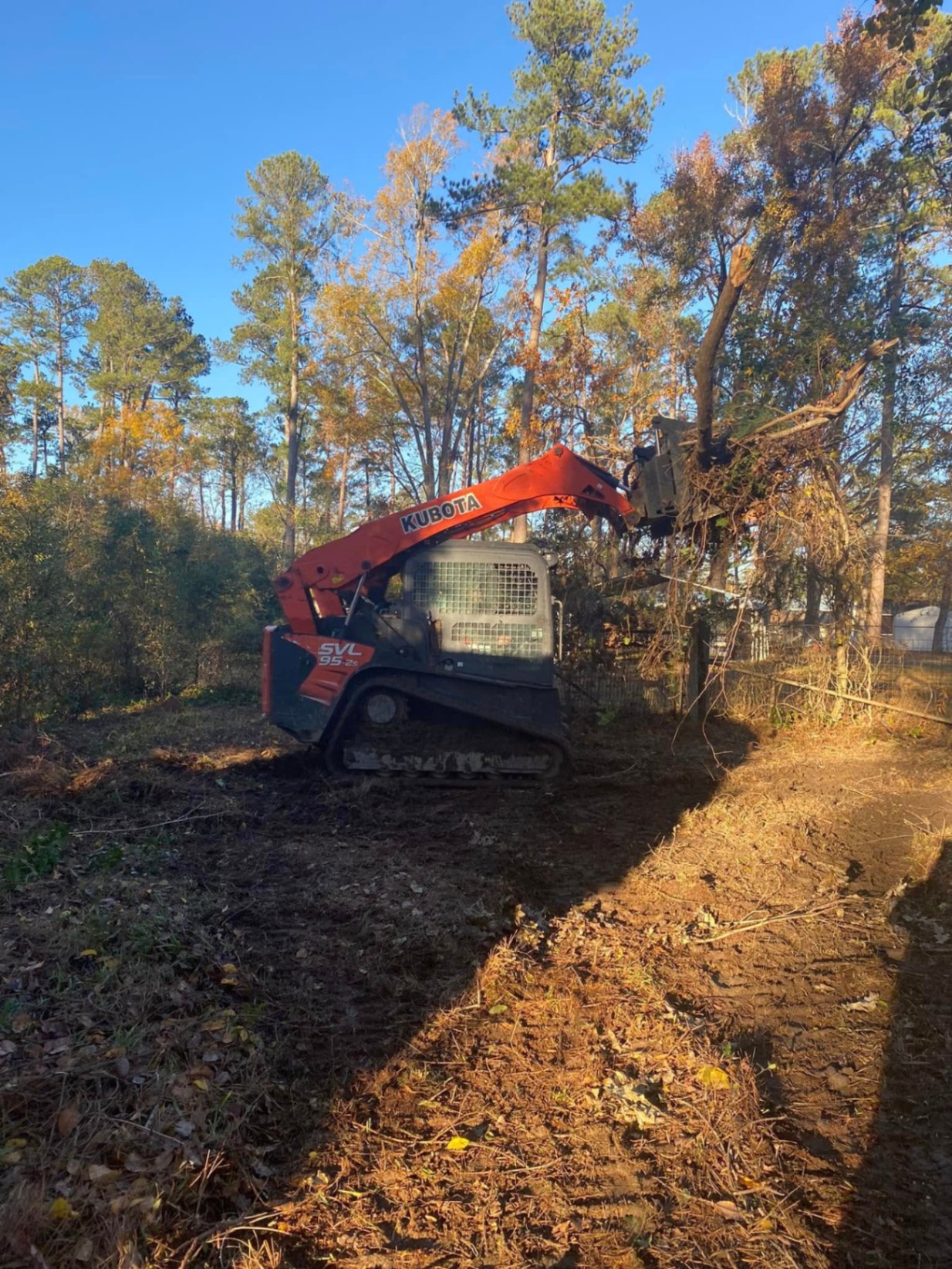 Kubota SVL95-2s skid steer clearing trees and brush